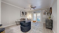 This well-appointed single-floor residence offers a thoughtfully designed layout that balances comfort and modern style throughout. Light wood-look flooring flows seamlessly across the entire space, complemented by neutral gray walls, crisp white crown molding, and clean baseboards that lend a polished, cohesive look.

The open-concept living area is bright and inviting, featuring a ceiling fan with light fixture and a set of French doors that flood the room with natural light and open onto a private balcony. The kitchen connects directly to the living space and is equipped with gray cabinetry, stainless steel appliances, a built-in microwave, and a peninsula island with bar seating — ideal for casual dining or entertaining.

The bedroom is generously sized, offering a ceiling fan, a window with outdoor views, and direct access to a well-proportioned bathroom. The bathroom features gray vanity cabinetry with a white countertop, and continues the light wood-look flooring found throughout the home. A spacious walk-in closet with built-in shelving and a dedicated hanging rod provides ample storage and organization.

Overall, the residence presents a clean, contemporary aesthetic with thoughtful finishes, an abundance of natural light, and a functional flow that makes every area of the space feel connected and livable.