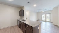 This single-floor residence offers five bedrooms and two bathrooms across a thoughtfully arranged floor plan. The open-concept kitchen and living area serves as the heart of the home, featuring a central island with granite countertops, dark espresso cabinetry, and a full suite of black appliances including a refrigerator, microwave, and dishwasher. A dedicated pantry provides generous additional storage. Light wood-style flooring flows seamlessly throughout the main living areas, complementing the neutral, warm wall tones. The living room is bright and airy, benefiting from natural light through French doors that open to an outdoor balcony, and is finished with a ceiling fan overhead. The bedrooms are well-proportioned, each with ceiling fans, wood-style flooring, and ample natural light from large windows. The primary bedroom offers direct access to an adjoining room and features generous closet space. The bathrooms are finished with large-format white tile flooring, dark vanity cabinetry with granite countertops, and tub-shower combinations with curved curtain rods. A hallway connects the various rooms, ensuring a practical and efficient layout throughout this comfortable, move-in-ready residence.