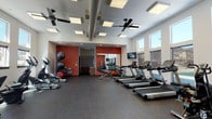 Located at 760 North Central Avenue in Moses Lake, Washington, this single-floor fitness center is designed to provide a comprehensive workout environment. The space features a clean, modern aesthetic with crisp white walls accented by bold terracotta-red feature walls that add energy and visual contrast throughout the room.

The facility is generously lit by a row of large windows along one wall, flooding the interior with natural light and offering views of the surrounding area. Overhead, recessed panel lighting and ceiling fans ensure consistent illumination and airflow across the entire floor space.

The cardio zone is well-appointed with multiple treadmills, stationary bikes, and elliptical machines, all positioned to take advantage of the natural light from the windows. Mounted flat-screen TVs provide entertainment options for those using the cardio equipment. A wall of mirrors enhances the sense of space and allows users to monitor their form during workouts.

The strength training area includes a cable machine system, adjustable bench, dumbbell rack, and stability balls, offering a range of resistance and functional training options. Durable rubber flooring covers the entire space, providing safety and sound absorption.

The fitness center also features a dedicated entryway with a mat and door access, ensuring a clean transition into the workout area. Overall, the space is thoughtfully laid out to support a variety of fitness routines in a bright, motivating environment.