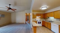 This single-floor unit offers a practical and comfortable layout designed for everyday living. The open-concept living area is generously sized, featuring plush carpeting, a ceiling fan, and a sliding glass door that floods the space with natural light and provides direct outdoor access. Baseboard heating is present throughout, ensuring year-round comfort.

The kitchen is well-equipped with warm oak cabinetry extending to the upper walls, offering ample storage. White appliances include an electric range, dishwasher, and double-basin sink. A tile floor ties the kitchen together, and a peninsula counter connects the kitchen to the living area, creating a seamless flow.

A hallway leads to two carpeted bedrooms, each featuring natural light from wood-framed windows and baseboard heaters. One bedroom includes a sliding closet door and direct access to the bathroom, functioning as a primary suite. The full bathroom is finished with tile flooring, an oak vanity with a mirror and lighted bar, and a tub-shower combination.

Warm wood trim, consistent neutral tones, and practical finishes create a cohesive and inviting atmosphere throughout this well-designed single-level space.
