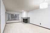 This single-floor residence offers a thoughtfully designed layout with a blend of comfort and functionality throughout. The open living area is anchored by a corner fireplace with a tiled surround, plush carpeting, and a large window that frames lush, wooded outdoor views, filling the space with natural light. A pendant light fixture adds a warm, welcoming ambiance to the room.

The kitchen is equipped with rich, dark cabinetry, granite countertops, and stainless steel appliances including a range and over-the-range microwave. A breakfast bar peninsula connects the kitchen to the main living and dining area, making it ideal for both everyday use and entertaining.

A long hallway with rich hardwood-style flooring connects the living spaces to the private areas of the home, including well-sized bedrooms carpeted for comfort, each benefiting from natural light through generously sized windows with wooded views.

The primary bathroom features hardwood-style flooring, a wide vanity with dark cabinetry, ample counter space, a large mirror, recessed lighting, and a walk-in glass-enclosed shower. A secondary bathroom offers a clean, functional design with a vanity and toilet. Throughout the space, neutral tones, dark wood accents, and consistent finishes create a cohesive and polished aesthetic.