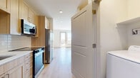 Located at 505 W Community Center Drive in Northglenn, CO, this thoughtfully designed one-bedroom, one-bathroom unit offers a bright and efficient layout finished with modern touches throughout. Light wood-tone luxury vinyl plank flooring runs continuously across the entire space, creating a warm and cohesive aesthetic.

The kitchen is well-appointed with light natural wood cabinetry, white quartz countertops, a white subway tile backsplash, and a full suite of stainless steel appliances including a range, over-the-range microwave, dishwasher, and refrigerator. A commercial-style pull-down faucet adds a refined detail to the undermount sink.

The open layout flows seamlessly from the kitchen toward the spacious bedroom, which benefits from abundant natural light through large windows and a private balcony door. A ceiling fan adds comfort, and the room connects directly to a generously sized walk-in closet with built-in shelving and hanging rods.

The bathroom features large-format neutral tile surrounding a full soaking tub with an overhead shower, complemented by light wood cabinetry and clean white fixtures. A dedicated laundry room houses a full-size side-by-side washer and dryer with overhead shelving, offering exceptional in-unit convenience. The overall ambiance is clean, contemporary, and move-in ready.