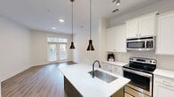 Located at 1226 Parktop Dr in Cary, NC, this single-story, one-bedroom, one-bathroom residence offers a well-planned layout with a thoughtful blend of comfort and functionality. Warm hardwood-style flooring runs throughout the unit, complementing the clean white walls and bright, neutral palette.

The open-concept kitchen and living area forms the heart of the home. The kitchen is outfitted with white shaker-style cabinetry, light quartz countertops, a tile backsplash, stainless steel appliances including a side-by-side refrigerator with ice and water dispenser, an electric range, and a built-in microwave. A kitchen island with an undermount sink and pendant lighting adds both workspace and style.

The living area benefits from natural light through French doors with transom windows, offering views of surrounding greenery. The spacious bedroom features a ceiling fan, a large window with outdoor views, and direct access to a walk-in closet with built-in shelving, as well as the full bathroom. The bathroom includes a soaking tub and shower combination with neutral tile surround and classic fixtures.

Completing the unit is a dedicated laundry room with a full-size washer and dryer and overhead shelving, along with a hallway connecting the main spaces for an efficient flow throughout.