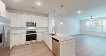 Located at 3240 Champion Ring Rd in Fort Myers, FL, this well-appointed single-story home offers two bedrooms, two bathrooms, and a thoughtfully designed open floor plan. The combined kitchen and living area serves as the heart of the home, showcasing a modern kitchen equipped with crisp white cabinetry, granite countertops, a subway tile backsplash, stainless steel appliances including a refrigerator, electric range, microwave, and dishwasher, and a central island with pendant lighting — ideal for both cooking and casual dining. Light wood-style flooring flows consistently throughout the home, enhancing the bright, clean aesthetic. The spacious primary bedroom connects directly to its own bathroom and features a ceiling fan, while the second bedroom is equally well-lit with a window and ceiling fixture. Both bathrooms are finished with granite-topped vanities and tub/shower combinations. The home includes three closets — one of which is a walk-in with wire shelving — as well as a dedicated laundry area and an outdoor patio. The neutral color palette, recessed lighting, and consistent finishes create a cohesive, move-in-ready environment throughout.