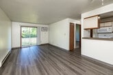 Located at 2100 King Ave in Des Moines, Iowa, this one-bedroom, one-bathroom unit offers a practical and well-organized layout across a single floor. The combined living and dining area is bright and open, featuring light-toned laminate flooring, a textured ceiling, and a sliding glass door that opens to a private balcony with outdoor views. A wall-mounted air conditioning unit and baseboard heating provide year-round climate control. The kitchen is designed in a galley style, offering ample cabinetry with warm wood accents, a double sink, a dishwasher, a range with microwave, and a full-size refrigerator. A pass-through counter connects the kitchen to the living and dining area, enhancing the sense of openness. The bedroom is carpeted for comfort and includes a large double sliding-door closet, a dedicated window that brings in natural light, and baseboard heating. Three closets throughout the unit provide generous storage options. The bathroom features a full tub-shower combination, a wood-trimmed vanity, and laminate flooring. A hallway connects the main living spaces, completing this efficiently designed and move-in-ready unit.