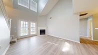 Located in Chattanooga, TN, this two-story residence offers a thoughtfully designed layout with a striking blend of comfort and modern finishes. The main living area immediately impresses with its dramatic vaulted ceilings that soar to great heights, creating an airy, open atmosphere bathed in natural light from upper clerestory windows. Light-toned hardwood-style flooring runs throughout the main level, complementing the neutral gray walls and crisp white trim. A corner fireplace with a classic white mantel serves as a focal point in the living room, while French doors provide seamless access to the outdoors and invite abundant natural light. The galley-style kitchen is well-equipped with stainless steel appliances, including a refrigerator, range, and dishwasher, alongside white cabinetry and light countertops. A breakfast bar connects the kitchen to an adjacent dining or living space, also finished with hardwood-style flooring and pendant lighting. An in-unit laundry area adds everyday convenience. A staircase with a white balustrade leads to the upper level, where carpeted bedrooms offer a quiet retreat. Bedrooms feature ceiling fans, ample closet space, and windows with outdoor views. At least one bedroom connects directly to a private bathroom. The overall ambiance is clean, bright, and move-in ready.