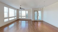 This single-floor residence offers a thoughtfully designed open-concept layout that blends comfort and functionality. The expansive living area is anchored by rich hardwood flooring, a ceiling fan, and a generous bank of windows that flood the space with natural light and offer outdoor views. An exposed industrial-style ductwork detail adds a contemporary loft-like character to the living and kitchen zones.

The kitchen is well-equipped with warm wood cabinetry, dark granite countertops, stainless steel appliances including a gas range, microwave, and French door refrigerator, complemented by a tile backsplash. A peninsula provides additional prep space and casual seating. A built-in desk nook with open shelving adjacent to the kitchen offers a convenient workspace.

The bedrooms are carpeted for comfort, each featuring ceiling fans and windows with outdoor views, creating bright and airy retreats. The primary bathroom is generously sized with a dual-sink vanity, soaking tub, separate glass-enclosed shower, recessed lighting, and tile flooring. A secondary full bathroom provides a tub-shower combination, a single vanity, and clean tile finishes. The overall ambiance of the residence is warm, modern, and move-in ready.