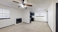 Located at 7302 University Row in San Antonio, TX, this single-floor, one-bedroom, one-bathroom unit offers a well-organized and functional layout. The open living area is a standout, featuring plush carpeting, a ceiling fan with a light fixture, and a classic fireplace that anchors the room with warmth and character. A textured ceiling adds a touch of architectural detail throughout the space.

The kitchen flows seamlessly from the living area and is equipped with bold, dark cabinetry paired with light countertops, a stainless sink with gold-toned fixtures, a dishwasher, and black appliances including a refrigerator and range. A white subway tile backsplash adds contrast, and a window allows natural light to brighten the space.

The bedroom is carpeted and comfortably sized, featuring its own ceiling fan, a window with blinds for natural light and privacy, and access to a mirrored closet with built-in shelving and hanging space. Dark-trimmed doors throughout the unit provide a consistent, modern aesthetic contrast against the white walls.

The bathroom includes a vanity with a stone-look countertop and dark cabinetry, a combination tub and shower, wood-look tile flooring, and gold accent hardware. This unit offers a practical and cohesive design suitable for comfortable everyday living.