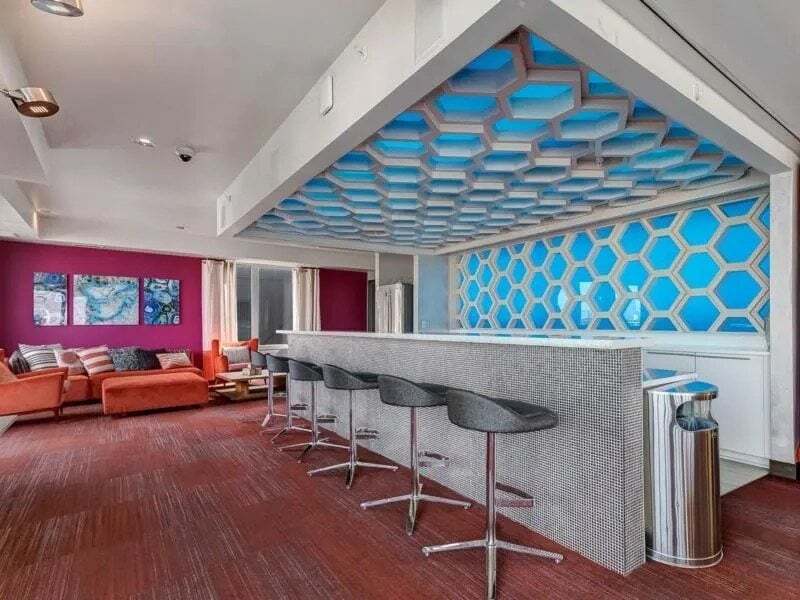 Modern lounge area with a bar, high-top stools, and comfortable seating.