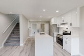 Located at 11127 110A Ave NW in Edmonton, Alberta, this well-appointed two-storey home offers a thoughtfully designed layout spread across two floors. The main floor hosts an open-concept kitchen and living area, where clean lines and modern finishes set the tone throughout. The kitchen is a standout feature, showcasing high-gloss white cabinetry with matte black hardware, a quartz waterfall island with an undermount sink, and stainless steel appliances including a french-door refrigerator and range. Recessed lighting and light-toned laminate flooring flow seamlessly into the living area, which is bathed in natural light from two large windows dressed with contemporary zebra blinds. A slim horizontal window in the living space adds an additional architectural touch. Upstairs, three bedrooms provide comfortable accommodation, including a generously sized primary bedroom with a dedicated closet. The additional bedrooms are well-proportioned, with windows offering natural light and neighbourhood views. Two full bathrooms serve the home — one featuring a glass-enclosed walk-in shower and white vanity, the other with a separate shower stall and matching finishes. A dedicated laundry area and two staircases complete the functional layout of this move-in-ready home.