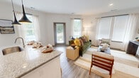 Located at 80 West Oxmoor Road in Birmingham, Alabama, this single-story, 2-bedroom, 2-bathroom residence offers a thoughtfully designed open-concept layout. Wood-look plank flooring runs throughout, complementing the clean white walls and contemporary finishes that define the space.

The combined kitchen and living area serves as the heart of the home. The kitchen is equipped with stainless steel appliances, warm wood cabinetry, subway tile backsplash, and a granite-topped island with pendant lighting and bar seating. The living area is bathed in natural light from multiple large windows with views to the outdoors, and a private exterior door provides additional access.

A welcoming entry hall connects the main living spaces to the private quarters. Both bedrooms offer natural light through large windows with a ceiling fan in the primary bedroom, which also features a spacious walk-in closet with extensive shelving and storage systems. Each bathroom is finished with wood-toned vanities, granite countertops, framed mirrors, and tiled walk-in showers with black hardware accents. A dedicated laundry area and pantry add practical convenience. The space also includes two closets, providing ample storage throughout.