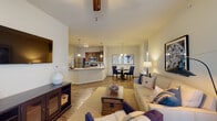This single-floor residence offers a thoughtfully designed open-concept layout that seamlessly connects the living, dining, and kitchen areas. The living room features soaring vaulted ceilings, warm wood-look flooring, and a ceiling fan, creating an airy and inviting atmosphere. A sliding door allows natural light to fill the space and provides access to the outdoors.

The kitchen is well-equipped with rich dark wood cabinetry, granite countertops, stainless steel appliances including a refrigerator, range, microwave, and dishwasher, and a breakfast bar that doubles as additional prep space. A dedicated dining area with pendant lighting sits adjacent, ideal for everyday meals or entertaining.

The bedroom offers plush carpeting, a large window with sheer curtains that invite natural light, and ample space for a full furniture arrangement. Two bathrooms mirror each other in design, both featuring dark wood vanities with granite countertops, large mirrors, and wood-look flooring. A convenient in-unit laundry closet houses a stacked washer and dryer.

Throughout the residence, a neutral color palette, consistent wood-look flooring in common areas, and cohesive finishes contribute to a clean, modern aesthetic that is both functional and comfortable.