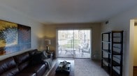 This well-appointed 2-bedroom, 2-bathroom single-floor residence offers a thoughtfully designed layout that balances comfort and functionality. The living area serves as the heart of the home, featuring warm, neutral-toned walls and plush carpeting that create an inviting atmosphere. A large sliding glass door floods the space with abundant natural light and opens directly onto a private outdoor patio, where seating and greenery provide a relaxing retreat. Vertical blinds offer flexible light control and privacy throughout the day. The open sightlines from the living room to the patio enhance the sense of spaciousness, making the interior feel connected to the outdoors. The two bedrooms provide comfortable private spaces, while the two full bathrooms add convenience for both residents and guests. The overall ambiance is warm and livable, with a layout that supports both relaxed daily routines and easy entertaining. The private patio is a standout feature, offering an accessible outdoor extension of the living space surrounded by lush landscaping — a welcoming touch that adds charm and character to this single-level home.