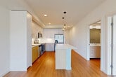 Located at 2681 Tagore Ave NE in Redmond, WA, this 1-bedroom, 1-bathroom residence offers a well-designed, single-level layout with a clean, modern aesthetic. The entry hallway leads directly into the open-concept kitchen and living area, where warm hardwood-style flooring extends throughout. The kitchen is a standout feature, showcasing white and light wood cabinetry reaching to the ceiling, a white quartz countertop island with pendant lighting overhead, a subway tile backsplash, and a full suite of stainless steel appliances including a french door refrigerator, electric range, and over-the-range microwave. Large windows at the living end of the space invite abundant natural light. The bedroom is comfortably proportioned, finished with plush carpet, a ceiling fan, and a window with exterior views. A sliding-door closet provides convenient storage, and an additional walk-in closet with wire shelving offers further organization. The bathroom features a wide vanity with light wood cabinetry, a full soaking tub and shower combo, and cool-toned accent walls. A dedicated laundry area completes this efficiently planned home, making it a practical and attractive option in the heart of Redmond.