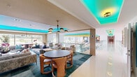 Located in Hot Springs, Arkansas, this expansive single-floor amenity facility offers a dynamic and thoughtfully designed environment across a generous footprint. A signature design element throughout the space is the striking teal LED cove lighting that crowns tray ceilings, lending a cohesive and contemporary energy to each area.

The main lounge is an eye-catching gathering space defined by bold red walls, red carpeting, and a vibrant tray ceiling accented in teal and yellow. Large floor-to-ceiling windows flood the room with natural light and offer views of the surrounding community, while a chandelier, flexible seating arrangements, and a dining area make it equally suited for socializing or events.

Adjacent lounge areas continue the sophisticated design with teal hexagonal tile accent walls, a linear fireplace, wall-mounted television, and eclectic furnishings. A quieter sitting nook features a plush leather sofa, rich gray cabinetry with panel detailing, and oversized windows framing outdoor views.

The private screening room is a cinematic retreat finished in deep charcoal tones, featuring tiered leather recliner seating with blue LED underlighting, oversized lounge bean bags, wall sconces, and a professional-grade projector.

The fitness center is spacious and light-filled, equipped with cycling bikes, resistance equipment, stability balls, and a large display screen. Ceiling fans, floor-to-ceiling mirrors, and equestrian-themed artwork complete the energetic yet refined atmosphere.
