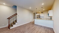 This well-designed two-story home offers a thoughtful layout with modern finishes throughout. The main level centers around an open-concept living and kitchen area, where durable hardwood-style flooring flows seamlessly underfoot. The kitchen is a standout feature, equipped with crisp white cabinetry, granite countertops, a subway tile backsplash, stainless steel appliances, and a large central island with an integrated sink — illuminated by a trio of stylish pendant lights. A staircase with a warm wood banister and black metal balusters connects the main level to the upper floor with understated elegance.

Upstairs, the bedrooms are bright and generously proportioned, featuring the same hardwood-style flooring, neutral wall tones, and windows that invite natural light. One bedroom offers vaulted ceilings that add a sense of volume, while another provides ample storage with multiple closets. Ceiling fans are present in select rooms for added comfort.

The bathrooms are clean and functional, each featuring a tub-shower combination with built-in shelving, brushed nickel fixtures, a dark-toned vanity, and light tile flooring. The overall aesthetic is neutral, modern, and move-in ready, with consistent finishes that give the home a cohesive and polished feel throughout both floors.
