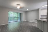 This three-story residence at 945 N Donahue Dr in Auburn, Alabama offers a well-organized layout distributed across multiple levels, connected by carpeted stairs with a sleek white handrail. Neutral-toned walls and consistent finishes throughout create a cohesive and understated aesthetic.

The kitchen is outfitted with white shaker-style cabinetry, dark granite countertops, and a full suite of stainless steel appliances, including a range, built-in microwave, and dishwasher. Wood-look luxury vinyl flooring and a window overlooking greenery add brightness and warmth to the space.

Living and common areas feature the same wood-look flooring and are bathed in natural light, with sliding glass doors providing access to a private balcony with views of surrounding trees. Ceiling fans with light fixtures are present throughout.

Bedrooms are carpeted and generously proportioned, each with ceiling fans and ample closet space. One bedroom features a wide bay-style window and walk-in closet. The primary bedroom connects directly to a private bathroom. Bathrooms are finished with white cabinetry, granite countertops, framed mirrors, and shower-tub combinations with wood-look flooring, maintaining a consistent design language across the entire home.