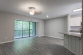 This three-story residence at 945 N Donahue Dr in Auburn, Alabama offers a well-organized layout distributed across multiple levels, connected by carpeted stairs with a sleek white handrail. Neutral-toned walls and consistent finishes throughout create a cohesive and understated aesthetic.

The kitchen is outfitted with white shaker-style cabinetry, dark granite countertops, and a full suite of stainless steel appliances, including a range, built-in microwave, and dishwasher. Wood-look luxury vinyl flooring and a window overlooking greenery add brightness and warmth to the space.

Living and common areas feature the same wood-look flooring and are bathed in natural light, with sliding glass doors providing access to a private balcony with views of surrounding trees. Ceiling fans with light fixtures are present throughout.

Bedrooms are carpeted and generously proportioned, each with ceiling fans and ample closet space. One bedroom features a wide bay-style window and walk-in closet. The primary bedroom connects directly to a private bathroom. Bathrooms are finished with white cabinetry, granite countertops, framed mirrors, and shower-tub combinations with wood-look flooring, maintaining a consistent design language across the entire home.