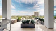 Located at 1317 Post Oak Park Drive in Houston's upscale Galleria/River Oaks corridor, this sophisticated rooftop terrace amenity space delivers an exceptional outdoor experience with refined design details throughout. The expansive terrace is finished in large-format light stone tile that lends a clean, contemporary aesthetic underfoot, seamlessly connecting multiple distinct zones across its generous footprint.

The space is organized into several purposeful areas. A covered lounge zone features soaring ceiling heights, ceiling fans for year-round comfort, and a wall-mounted flat-screen television, creating an al fresco living room atmosphere. Plush outdoor seating arrangements with crisp white cushions and colorful accent pillows are positioned throughout, alongside a substantial fire pit bowl that serves as a focal point for evening gatherings. A billiards table adds a recreational element to the covered entertainment section, complemented by bistro-height seating.

An open-air terrace section offers panoramic views of the Houston skyline and lush treetop canopy below, framed by sleek glass railings that preserve unobstructed sightlines. Architectural planters filled with bold agave and sculptural boxwood topiaries introduce vibrant greenery. Floor-to-ceiling glass walls along the interior façade allow views into an adjacent fitness center, reinforcing the space's role as a premium amenity destination. Natural light floods the entire terrace throughout the day.
