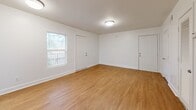 Located at 320 Fairburn Rd SW in Atlanta, Georgia, this 2-bedroom, 1-bathroom unit offers a efficiently organized single-level layout. The living room serves as the central gathering space, featuring warm wood-look laminate flooring, crisp white walls, and flush-mount ceiling lighting. A window along one wall admits natural light, while an open sightline connects the area directly to the galley-style kitchen.

The kitchen is a functional, well-appointed corridor space featuring white shaker-style cabinetry with matte black hardware, granite-look countertops with an undermount sink, and stainless steel appliances including a refrigerator, electric range, and microwave. Wood-look flooring and recessed lighting complete the clean, modern aesthetic.

Both bedrooms are carpeted and feature windows that bring in natural light with outdoor views of surrounding greenery. The primary bedroom includes two closets—one standard door and one louvered—providing practical storage. A hallway connects the bedrooms to the full bathroom, which includes a white tub-shower combination with chrome fixtures. The unit's consistent white palette and updated finishes throughout contribute to a clean, move-in-ready appearance.