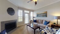 This single-story 1-bedroom, 1-bathroom residence offers a well-designed layout that maximizes comfort and functionality. The living room serves as the heart of the home, featuring plush carpeting, crown molding, a ceiling fan, and a tile-surround fireplace. A French door flanked by large windows with plantation-style blinds floods the space with natural light while providing outdoor access. A dedicated dining area sits adjacent to the living space, accented by chair rail molding and wall art, creating a defined yet open setting. The galley-style kitchen is outfitted with dark cabinetry, granite-style countertops, black appliances including a refrigerator, range, microwave, and dishwasher, along with wood-look flooring that adds warmth and durability. The bedroom is a serene retreat with plush carpet, a ceiling fan, generous window exposure, and a closet with panel doors. The full bathroom features wood-look tile flooring, a dark vanity with stone countertops, and a full tub and shower combination. Throughout the residence, neutral tones and consistent finishes create a cohesive and inviting atmosphere well-suited for everyday living.