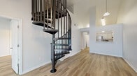 This two-story residence offers 2 bedrooms and 3 bathrooms across a well-utilized floor plan, with the main level comprising the majority of the living space. A standout architectural feature is the sleek, dark metal spiral staircase that rises dramatically from the main living area to the upper level, complemented by soaring vaulted ceilings that lend an airy, open feel to the space. Light wood-style flooring runs consistently throughout, tying the rooms together with a clean, cohesive aesthetic.

The kitchen is fitted with white raised-panel cabinetry, light countertops, and stainless steel appliances, including a range and refrigerator. A pass-through window connects the kitchen to the living area, enhancing the sense of openness and facilitating easy interaction between spaces.

Both bedrooms feature vaulted ceilings, ceiling fans with light fixtures, and windows that invite natural light and outdoor views. The primary bedroom offers a generous footprint with ample room for furnishings. The bathrooms are finished consistently with white cabinetry, stone-toned countertops, tub-shower combinations, and warm wood flooring, giving each a tidy, functional appearance.

The overall ambiance is bright, neutral, and move-in ready, with a modern yet approachable character throughout.