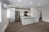 Located at 143 Main St S in Brampton, Ontario, this well-appointed one-bedroom, one-bathroom unit offers a thoughtfully designed layout across a single floor. Light-toned luxury vinyl plank flooring runs throughout, lending a clean, cohesive aesthetic to every room.

The kitchen is a standout feature, showcasing white shaker-style cabinetry extending to the ceiling, sleek white quartz countertops, a full suite of stainless steel appliances including a refrigerator, electric range, and over-the-range microwave, and a functional peninsula that provides additional prep and dining space. Recessed pot lighting illuminates the area effectively.

The open living area is bright and inviting, benefiting from a large window that invites natural light and offers street views. Crown moulding adds a refined architectural detail to the space.

The bedroom is a comfortable size, featuring a window for natural light, a baseboard heater, and a dedicated closet with double doors and a full-width hanging rod, providing generous storage.

The bathroom is clean and modern, featuring a sliding glass-enclosed shower/tub combination, a white vanity with storage, and warm wood-toned flooring. A connecting hallway ties the layout together efficiently, making this unit a practical and attractively finished living space.