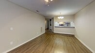 This single-floor residence offers a thoughtfully designed layout with a comfortable mix of living and private spaces. The living room serves as a central gathering area, featuring warm hardwood-style flooring, a classic fireplace with a white mantle, a ceiling fan, and a window that brings in natural light. Adjacent to the living area, the dining space is illuminated by an elegant chandelier that adds a touch of refinement to the open floor plan. The kitchen is efficiently arranged with white cabinetry, gray countertops, a stainless steel refrigerator, an electric range, and a stainless steel sink — all connected to the main living area via a pass-through counter window. The bedrooms are finished with plush carpeting and ceiling fans, providing comfort throughout. One bedroom features mirrored bifold closet doors with built-in shelving, while another includes vertical blinds offering privacy and light control. The bathrooms are clean and functional, with one featuring a full tub-shower combination with built-in wall niches. Neutral tones and consistent finishes throughout the home create a cohesive and inviting atmosphere well-suited for everyday living.