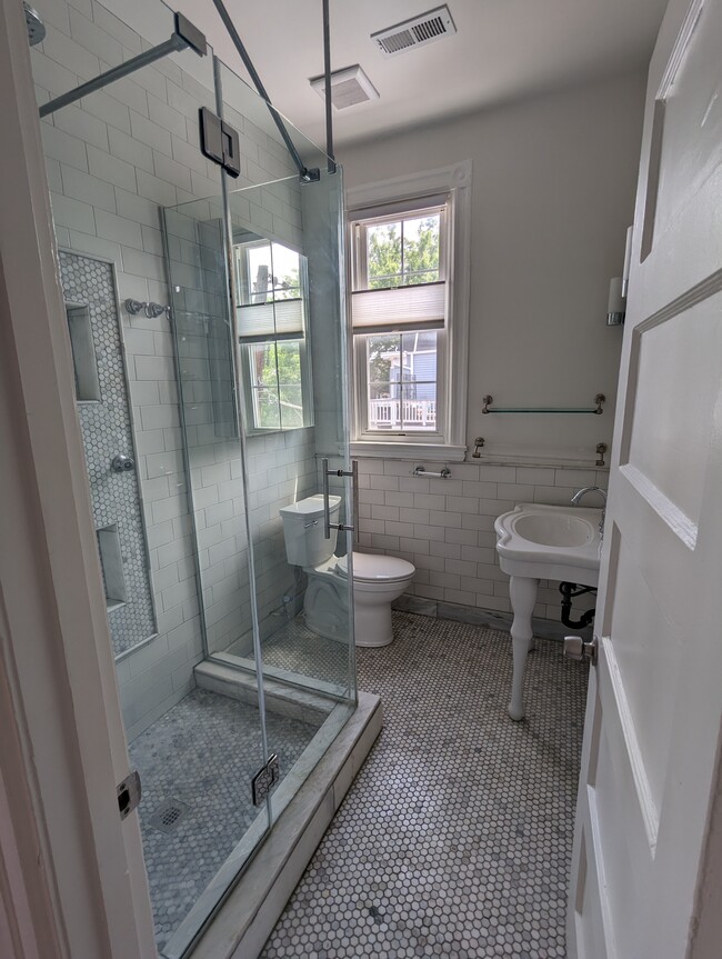 Marble tiled bathroom with glass shower and console sink. - 4413 GEORGIA AVE NW