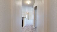 This single-story, 3-bedroom, 2-bathroom home offers a thoughtfully designed layout that maximizes comfort and functionality. The entrance opens through a hallway with a distinctive arched architectural detail, leading into a combined kitchen and living area. The kitchen features warm wood cabinetry, dark granite-style countertops with a breakfast bar peninsula, and a black appliance suite, all illuminated by bright overhead lighting. The adjoining living room is generously sized, featuring plush neutral carpeting, a ceiling fan, and a set of windows with a glass door that invites abundant natural light and outdoor views. A decorative wainscoting accent adds character to the dining area. The three bedrooms are carpeted and well-proportioned, with the spacious primary bedroom offering ample room to furnish. Each bedroom benefits from large windows with exterior views and ceiling fans for year-round comfort. Both bathrooms are finished with wood-toned cabinetry, dark countertops, and a tub-shower combination, with one bathroom featuring warm hardwood-style flooring. Textured walls throughout the home add a layer of visual interest, and the neutral color palette creates a clean, inviting ambiance across every room.