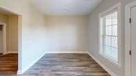 This well-appointed unit at 380 Mather St in Hamden, Connecticut, offers a thoughtfully designed single-floor layout that makes excellent use of its compact footprint. The combined kitchen and living area forms the heart of the space, characterized by rich dark-espresso cabinetry, granite countertops, and a full suite of stainless steel appliances — including a gas range, built-in microwave, and dishwasher — all set atop durable wood-look flooring that flows throughout the unit. Natural light pours in through multiple windows fitted with classic white horizontal blinds, creating a bright and airy atmosphere. A glass-panel door opens directly onto a private balcony, extending the living space outdoors and offering pleasant views of the surrounding neighborhood. The living area features neutral-toned walls and clean white trim, lending the space a modern yet welcoming ambiance. The bathroom is finished with a dark wood vanity, a framed mirror, and consistent wood-look flooring, maintaining a cohesive aesthetic throughout. A hallway connects the key areas efficiently, contributing to the unit's functional flow. Clean lines, contemporary finishes, and abundant natural light define the overall character of this streamlined residence.