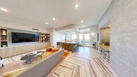Located at 2500 SW 22nd Terrace in Fort Lauderdale, Florida, this thoughtfully designed amenity space spans a generous single floor, offering residents a well-rounded environment for relaxation and entertainment. The layout encompasses two distinct living areas and a dedicated game room, each finished with a cohesive modern aesthetic.

The first living area serves as a comfortable lounge, featuring a built-in wood-paneled media wall with open shelving, a large flat-screen TV, and warm neutral furnishings including plush seating and accent tables. Colorful artwork adorns the walls, adding a curated, residential feel to the space.

The game room is a standout feature, anchored by a full-size pool table beneath a cluster of modern pendant lights. A striking chevron-patterned hardwood floor adds visual depth, while a foosball table, booth-style seating with warm wood accents, and ambient LED lighting complete the upscale, social atmosphere.

The second living area transitions seamlessly to a covered outdoor terrace, where light wood-toned flooring extends the interior palette outside. The terrace is furnished with contemporary round tables and mixed seating, all set against an open railing that reveals expansive views of the Fort Lauderdale skyline and lush tree canopy below. Natural light floods both the interior and exterior spaces, creating a bright and airy ambiance throughout.