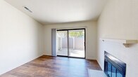 Located at 5220 N Brawley Ave in Fresno, CA, this single-story 2-bedroom, 1-bathroom unit offers a well-organized layout across a comfortable footprint. The open-concept kitchen and living area serves as the heart of the home, featuring light maple cabinetry, stainless steel appliances including a refrigerator, range, and microwave, white countertops, a double basin sink, and a peninsula with bar-height seating potential. Rich hardwood-style flooring runs throughout the main living areas, complementing the warm, neutral palette. The living room benefits from vaulted ceilings that enhance the sense of openness, a ceiling fan with integrated lighting, and a classic fireplace with a white mantel as a focal point. Sliding glass doors lead to a private outdoor patio, filling the space with natural light. Both bedrooms are carpeted and generously proportioned, each with windows offering outdoor views and ceiling fans for added comfort. The primary bedroom provides direct access to the bathroom, which includes a vanity with wood cabinetry, white countertops, and a shower-tub combination with a glass enclosure. A dedicated closet and hallway complete the floor plan, providing practical storage. The overall ambiance is clean, bright, and move-in ready.