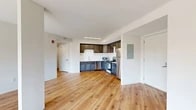 This well-appointed two-bedroom, two-bathroom unit at 100 Reserve Road in Danbury, CT offers a thoughtfully designed single-floor layout with a clean, modern aesthetic throughout. The open-concept living and kitchen area serves as the heart of the home, anchored by warm hardwood-style flooring that extends seamlessly across the entire unit. The kitchen is equipped with a full suite of stainless steel appliances — including a gas range, refrigerator, dishwasher, and microwave — complemented by rich dark-toned upper cabinetry, two-toned lower cabinetry, light countertops, and a classic white subway tile backsplash. The spacious living area flows naturally from the kitchen, offering generous room for everyday living. The primary bedroom features a wall-mounted mini-split HVAC unit and a dedicated closet with wire shelving. The second bedroom is highlighted by a large picture window that invites abundant natural light and frames views of surrounding trees. Both bathrooms are finished in clean white tones with tub-shower combinations and hardwood-style flooring. A hallway connects the private areas of the unit. The space also includes a dedicated walk-in closet with wire shelving, adding practical storage solutions throughout.