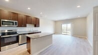 This well-appointed one-bedroom, one-bathroom unit on the third floor at 4750 Innovation Dr. in Lincoln, NE offers a thoughtfully designed open-concept layout that maximizes its comfortable footprint. Light-toned luxury vinyl plank flooring flows throughout the main living areas, lending a clean, contemporary feel.

The kitchen is a standout feature, showcasing rich dark-brown cabinetry extending to the ceiling for ample storage, granite countertops, stainless steel appliances including a refrigerator, range, and microwave, and a central island that provides additional prep space and casual seating. The kitchen opens seamlessly into the living room, which is filled with natural light and provides direct access to a private balcony through sliding glass doors, offering pleasant outdoor views.

The bedroom is carpeted for comfort, features a ceiling fan, and connects to a generous walk-in closet outfitted with built-in shelving and hanging rods for organized storage. The full bathroom is finished with dark cabinetry, granite countertops, a tub-shower combination, and light hardwood-style flooring, maintaining a consistent design aesthetic throughout. Neutral wall tones and recessed lighting complete the polished, move-in-ready ambiance of this unit.