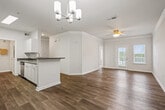 This single-floor residence offers a thoughtfully designed layout encompassing two bedrooms, two bathrooms, a combined dining room and kitchen, a hallway, and two closets. Wood-look plank flooring flows throughout the main living and kitchen areas, complemented by crisp white baseboards and crown molding that lend a polished, cohesive aesthetic.

The kitchen features white cabinetry, dark speckled countertops, a double stainless steel sink, and stainless steel appliances, including a refrigerator, microwave, and range. A peninsula with additional counter space connects the kitchen to the dining area, which is accented by a modern chandelier. The primary bedroom offers plush carpeting, natural light through two windows with blinds, and a ceiling fan. It is supported by a spacious walk-in closet equipped with wire shelving systems for organized storage. The second bedroom is similarly carpeted and well-proportioned. Both bathrooms include white vanity cabinetry, dark countertops, large mirrors, and tile shower enclosures. The connecting hallway is bright and open, providing smooth transitions between all areas of the home.