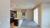 This single-story residence is designed around an open-concept layout that seamlessly connects the kitchen, dining, and living areas. The kitchen is a standout feature, equipped with dark espresso cabinetry, granite countertops, stainless steel appliances including a refrigerator, dishwasher, and range, and a central island that provides additional workspace and seating. Pendant lighting and a track light system illuminate the kitchen, while wood-look flooring adds warmth underfoot.

The living area is finished with plush carpeting and features a ceiling fan and a large sliding glass door fitted with vertical blinds, allowing natural light to filter through. An in-unit laundry area is conveniently accessible from the main living space, adding notable practicality.

The bedroom is carpeted and well-lit by multiple windows, including elevated clerestory windows, with a ceiling fan providing added comfort. The bathroom is finished with wood-look flooring, a dark vanity with light countertops, and a walk-in shower enclosed by sliding glass doors with chrome hardware. Throughout the residence, neutral tones and consistent finishes create a cohesive and functional living environment.