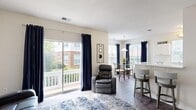 Located at 7300 Southwind Drive in Chesterfield, VA, this single-floor, 2-bedroom, 2-bathroom home offers a comfortable and functional layout. The open-concept living and dining area is bathed in natural light from large sliding glass doors that lead to a private balcony overlooking the surrounding greenery. The living room features wood-style flooring, neutral walls, and a textured ceiling, creating a bright and welcoming atmosphere. Adjacent to the living area, the dining room includes a pendant light fixture and large windows dressed with navy curtains, providing an inviting space for meals. The kitchen is outfitted with white cabinetry, light countertops, black appliances, and a window above the sink that lets in additional natural light. A hallway connects the main living spaces to the two bedrooms, each featuring plush carpeting and ample closet space. The primary bedroom is generously sized, while the second bedroom also offers a comfortable retreat with a large window. Both bathrooms are well-appointed, with one featuring a soaking tub, white tile with a green checkered accent border, and wood-style flooring. A dedicated closet in the hallway adds convenient storage throughout this thoughtfully designed home.