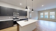 Located at 51 Okner Pkwy in Livingston, NJ, this well-appointed 2-bedroom, 2-bathroom residence offers a thoughtfully designed single-floor layout with modern finishes throughout. The open-concept kitchen and living area serves as the heart of the home, showcasing dark cabinetry with gold-tone hardware, a subway tile backsplash, stainless steel appliances including a gas range, microwave, and French door refrigerator, and a sleek white quartz island with an undermount sink. Pendant lighting adds a contemporary touch overhead, while light hardwood flooring flows seamlessly throughout the entire space. The primary bedroom is generously sized, featuring a bank of large windows that invite natural light and offer views of the surrounding neighborhood. The second bedroom is equally bright, also benefiting from oversized windows. Three closets provide abundant storage, including a walk-in closet outfitted with wire shelving systems. Both bathrooms are finished with marble-look tile flooring, dark vanities with white countertops, and glass-enclosed showers. A dedicated laundry area adds everyday convenience. Recessed lighting, neutral wall tones, and clean architectural lines create a cohesive, contemporary ambiance throughout.