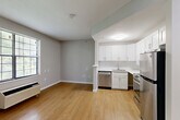 Located at 8710 Research Dr in Charlotte, NC, this single-floor unit offers a well-organized layout comprising a living room, one bedroom, and a closet. Warm hardwood-style flooring runs throughout the space, lending a cohesive and clean aesthetic to every room.

The open living area is bright and airy, featuring large windows with blinds that invite abundant natural light and offer views of surrounding greenery. A wall-mounted HVAC unit provides climate control, and clean neutral gray walls create a calm, versatile backdrop.

The kitchen is efficiently designed and seamlessly connected to the living area via a partial partition. It features white shaker-style cabinetry, white subway tile backsplash, light countertops, and a full suite of stainless steel appliances including a refrigerator, dishwasher, and range — offering both function and a modern aesthetic.

The bedroom is a comfortable, well-proportioned room with its own window allowing natural light and outdoor views, along with a wall-mounted HVAC unit. Neutral walls and hardwood-style flooring continue here, maintaining the consistent design language of the unit. A dedicated closet provides practical storage.

The hallway connecting the rooms features recessed lighting and a classic six-panel white door, completing this tidy, move-in ready space in Charlotte.