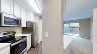 Located at 5664 Walnut Ave in Downers Grove, IL, this well-appointed one-bedroom, one-bathroom unit offers a thoughtfully designed single-floor layout. The open-concept kitchen is a standout feature, boasting white shaker cabinetry, a large quartz peninsula with an undermount sink, and a full suite of stainless steel appliances including a refrigerator, electric range, and microwave. Wood-look flooring runs throughout the kitchen, which also provides convenient access to in-unit laundry. The living room is generously proportioned with plush carpeting, neutral taupe walls, and a full-width sliding glass door that opens to a private balcony, flooding the space with natural light and outdoor views. The bedroom is a comfortable retreat, featuring soft carpet, neutral tones, and two windows that bring in additional daylight. A spacious walk-in closet with wire shelving offers ample storage. The bathroom is clean and functional, featuring a tiled tub-shower combination, a white vanity with a quartz countertop, built-in cabinetry, and wood-look tile flooring. The overall aesthetic throughout is modern and move-in ready, with a cohesive neutral palette.