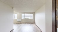 Located at 1900 Naval Ave in Bremerton, Washington, this one-bedroom, one-bathroom unit offers a well-organized, efficient layout across a single floor. The living area is bright and open, featuring light wood-tone flooring, a textured ceiling, and a bank of large windows that frame serene waterfront views — a standout feature of the space. A wall-mounted baseboard heater keeps the area comfortable year-round.

The kitchen is designed for functionality, featuring rich dark wood cabinetry — both upper and lower — paired with clean white countertops and a stainless steel refrigerator. A deep sink sits centrally along the counter, and the galley-style layout makes efficient use of the available space.

The bedroom is a well-proportioned, quiet retreat with its own window for natural light and a baseboard heater. It provides direct access to a dedicated walk-in closet equipped with shelving and hanging rods for generous storage. An additional closet elsewhere in the unit offers further organizational flexibility.

The bathroom features warm dark wood cabinetry beneath a white countertop vanity, a large mirror, and light wood-tone flooring consistent with the rest of the unit. The overall aesthetic throughout is clean, neutral, and modern, making this a practical and comfortable living space.
