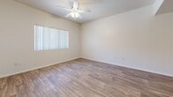 Located in Glendale, Arizona, this single-story 2-bedroom, 1-bathroom unit offers a practical and well-organized layout. Wood-look flooring runs throughout the main living areas and hallway, lending a cohesive, clean aesthetic. The living room is bright and open, featuring a ceiling fan and a large window with vertical blinds that allows natural light to fill the space. The kitchen is efficiently designed with light wood cabinetry, granite-look countertops, a double basin sink, and a black dishwasher, along with a pantry-style closet for additional storage. A connecting hallway with an arched doorway detail leads to the rest of the unit. Both bedrooms are carpeted and include ceiling fans and natural light from windows with vertical blinds. The primary bedroom offers a double sliding mirrored closet, while the second bedroom features a pair of built-in closets with paneled doors. The bathroom is clean and functional, showcasing a warm wood-tone vanity with a stone-look countertop, a tiled shower-tub combination, and wood-look flooring that ties the space together. The unit's neutral palette and consistent finishes create a cohesive and move-in ready environment.