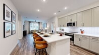This well-appointed 2-bedroom, 2-bathroom residence in Centennial, Colorado offers a thoughtfully designed single-floor layout that balances comfort and modern style. The open-concept living and kitchen area serves as the heart of the home, where wood-style plank flooring flows seamlessly throughout. The kitchen is equipped with stainless steel appliances — including a refrigerator, range, and built-in microwave — complemented by soft gray shaker cabinetry, white quartz countertops, a subway tile backsplash, and a large center island with bar seating, ideal for casual dining or entertaining. The living room receives abundant natural light through a large window with views of the surrounding community. The primary bedroom features plush carpet, a ceiling fan, sliding glass doors to an outdoor area, and a dedicated closet with built-in shelving. The second bedroom is equally well-sized with carpeted floors and its own closet. Both bathrooms are finished with light tile, sage-toned cabinetry, white countertops, and black hardware accents. Additional highlights include two laundry areas, a mudroom-style entry with built-in storage, and recessed lighting throughout, creating a bright, cohesive ambiance across the entire residence.