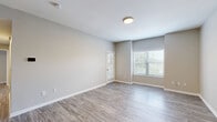 Located at 7987 N Flintlock Rd in Kansas City, Missouri, this single-floor, 3-bedroom, 2-bathroom home offers a practical and well-appointed layout. The living room features wood-look luxury vinyl plank flooring and neutral warm-toned walls, with natural light streaming in through windows fitted with white blinds, creating a clean and inviting atmosphere. The kitchen is efficiently designed with white cabinetry, white countertops, a classic subway tile backsplash, and a full suite of stainless steel appliances including a refrigerator, electric range, and microwave. In-unit laundry is conveniently accessible just off the kitchen. The three bedrooms are carpeted in a warm, neutral tone, each offering comfortable proportions. The primary bedroom provides a generous footprint and ample natural light via a large window overlooking greenery. The two bathrooms maintain a consistent, clean aesthetic with wood-look LVP flooring, white vanity cabinetry, and bright lighting. One bathroom features a bathtub, while the other offers a vanity with a mirror and window. The home's consistent neutral palette, mixed flooring materials, and functional layout make it a well-organized and comfortable living space.