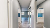 Located on Saticoy Street in Van Nuys, Los Angeles, this efficiently designed single-floor unit offers a well-organized layout comprising a living room, kitchen, bathroom, hallway, and closet. Cool-toned gray walls and light wood-look vinyl flooring run consistently throughout, lending the space a clean, cohesive aesthetic.

The hallway serves as the central connector of the unit, featuring elegant arched doorways and a full-length mirrored sliding closet that adds depth and practicality. The living room is an open, bright space with light gray walls, large windows that invite natural light and views of the surrounding neighborhood, and a wall-mounted air conditioning unit for year-round comfort.

The galley-style kitchen is neatly arranged with white cabinetry, light countertops, a stainless steel sink, and a full-size refrigerator, making efficient use of the available space. The bathroom is clean and functional, featuring a tub-shower combination with a curtain, a white vanity, and the same wood-look flooring that flows throughout the rest of the unit.

Crisp white baseboards and trim provide a sharp contrast against the muted wall tones, contributing to an overall atmosphere that feels fresh, modern, and move-in ready. The thoughtful layout maximizes every inch of the space.