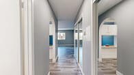 Located on Saticoy Street in Van Nuys, Los Angeles, this efficiently designed single-floor unit offers a well-organized layout comprising a living room, kitchen, bathroom, hallway, and closet. Cool-toned gray walls and light wood-look vinyl flooring run consistently throughout, lending the space a clean, cohesive aesthetic.

The hallway serves as the central connector of the unit, featuring elegant arched doorways and a full-length mirrored sliding closet that adds depth and practicality. The living room is an open, bright space with light gray walls, large windows that invite natural light and views of the surrounding neighborhood, and a wall-mounted air conditioning unit for year-round comfort.

The galley-style kitchen is neatly arranged with white cabinetry, light countertops, a stainless steel sink, and a full-size refrigerator, making efficient use of the available space. The bathroom is clean and functional, featuring a tub-shower combination with a curtain, a white vanity, and the same wood-look flooring that flows throughout the rest of the unit.

Crisp white baseboards and trim provide a sharp contrast against the muted wall tones, contributing to an overall atmosphere that feels fresh, modern, and move-in ready. The thoughtful layout maximizes every inch of the space.
