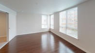 Located on the fourth floor at 13280 Linden Ave N in Seattle's Shoreline neighborhood, Unit 425 is a well-appointed single-floor residence designed with clean lines and a modern aesthetic throughout. The open living area is highlighted by rich, dark hardwood flooring that extends across the main living space, reflecting natural light that pours in through large corner windows. These generous windows offer views of the surrounding neighborhood and fill the room with an airy, bright atmosphere. The layout flows naturally from the living area toward the kitchen, which features light maple cabinetry, white countertops, a stainless steel sink, and GE stainless steel appliances including an electric range and over-the-range microwave. The kitchen is efficient and well-organized, providing ample storage and workspace. The bedroom is carpeted for comfort and maintains the unit's clean, neutral color palette. It includes a sliding-door closet with a built-in rod and shelving system, offering practical storage. A dedicated hallway connects the bedroom to the rest of the unit, contributing to a functional and private layout. Throughout the space, neutral wall tones and white trim provide a versatile backdrop suited to a variety of interior styles. The unit presents a comfortable, modern living environment in a well-established Seattle residential community.