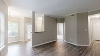 Located in Jersey Village, TX, this single-story, 3-bedroom, 2-bathroom home offers a well-designed layout with thoughtful finishes throughout. The living area features wood-look luxury vinyl plank flooring, crown molding, and neutral taupe walls that create a warm, cohesive atmosphere. A ceiling fan and glass French doors with flanking windows fill the space with natural light and provide outdoor views. A built-in cabinet with a dark granite top adds a functional architectural detail to the living or dining area, which is also brightened by dual windows overlooking greenery outside. The kitchen is equipped with light wood cabinetry, dark granite countertops, a tile backsplash, white appliances, and tile flooring. A pantry with wire shelving provides convenient additional storage. The primary bedroom offers plush carpeting, crown molding, and access to a spacious walk-in closet with wire shelving and hanging rods. The secondary bedrooms are carpeted and include mirrored sliding closet doors. Both bathrooms feature tub/shower combos with white tile surrounds accented by a classic black diamond border, set atop durable tile flooring. A dedicated in-unit laundry room with side-by-side washer and dryer hookups adds everyday convenience to this well-appointed home.