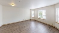 Located at 4342 S Pine St in Tacoma, Washington, this two-story home offers a well-organized layout with functional living spaces spread across both levels. The main floor features an open-concept kitchen equipped with light maple cabinetry, tile countertops, a built-in microwave, an electric range, and a full-size refrigerator — all in a sleek black finish. A skylight above the kitchen adds natural brightness, while a peninsula with bar seating connects the kitchen to the adjacent living areas. The main living spaces are finished with wood-look laminate flooring, lending a clean and modern aesthetic throughout. A dedicated room on the main level with a ceiling fan and large window provides a versatile space ideal for a home office or dining area. Upstairs, the carpeted bedrooms offer a quiet retreat, with generously sized rooms featuring neutral tones and windows that frame views of the surrounding neighborhood and lush greenery. The lower level includes additional carpeted living space with staircase access, providing flexible room for recreation or storage. Throughout the home, soft neutral walls, warm wood-toned trim, and an abundance of natural light from well-placed windows create a bright, welcoming ambiance.